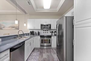 a kitchen with white cabinets and a stainless steel refrigerator at Serene Oasis - Home Away from Home in Honokai Hale