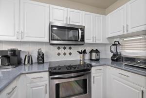 a kitchen with white cabinets and a microwave at Serene Oasis - Home Away from Home in Honokai Hale