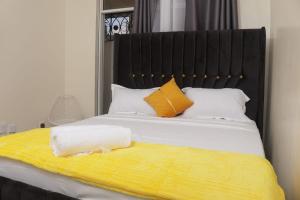 Una cama con una manta amarilla y dos almohadas encima. en Cosy apartments, en Mtwapa