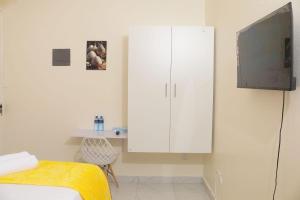 Un dormitorio con un armario blanco y un televisor. en Cosy apartments, en Mtwapa