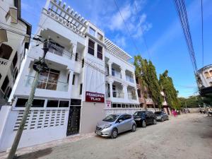 dos autos estacionados frente a un edificio blanco en Cosy apartments, en Mtwapa