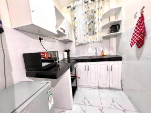 Una cocina blanca con microondas y fregadero. en Cosy apartments, en Mtwapa