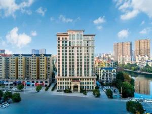 a large building in a city next to a body of water at Vienna Hotel Henan Xinyang East Zone of Central Hospital in Pingqiao