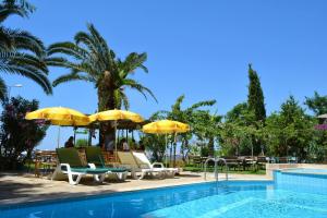 a pool with chairs and umbrellas next to a resort at Palmiye Hotel in Özdere