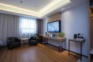 a hotel room with a desk and a tv on a wall at Gya Hotel Beijing Shunyi Yanjing Bridge in Shunyi