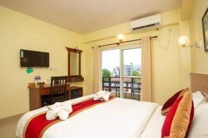 a bedroom with a bed and a desk and a window at Hotel Dream Light in Pokhara