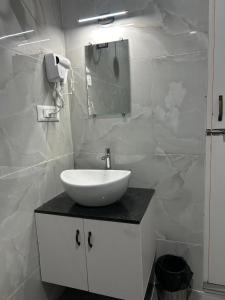 a white bathroom with a sink and a mirror at Hotel Park Land in Kodaikānāl
