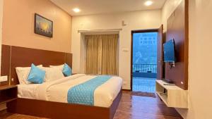 a bedroom with a bed and a television and a balcony at Hotel Park Land in Kodaikānāl
