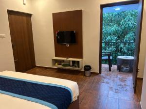 a bedroom with a bed and a tv and a balcony at Hotel Park Land in Kodaikānāl +25 photos