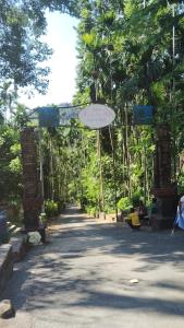 ein Gehweg mit einem Bogen, gesäumt von Bäumen und einem Schild in der Unterkunft Tribe Riverbank Campsite in Dawki