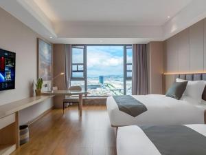 sypialnia z łóżkiem, biurkiem i dużym oknem w obiekcie Gya Hotel Kunming Zijin Center Xiaodongcun Metro Station w mieście Kunming