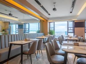 restauracja ze stołami i krzesłami oraz dużymi oknami w obiekcie Gya Hotel Kunming Zijin Center Xiaodongcun Metro Station w mieście Kunming