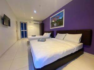 Un dormitorio con dos camas y una pared morada. en Hotel Double Star Klia, en Sepang