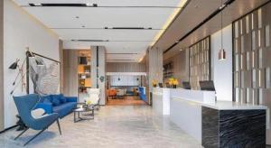 a lobby with blue chairs and a living room at Echarm Hotel Shenzhen International Exhibition Center Fuyong in Fenghuangwei