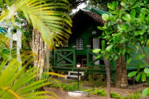 una casa verde con una panchina davanti di Le Jardin Arhumatic Sambava a Sambava