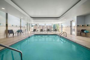 ein Pool in einem Hotel mit Stühlen und Tischen in der Unterkunft Courtyard Des Moines Ankeny in Ankeny