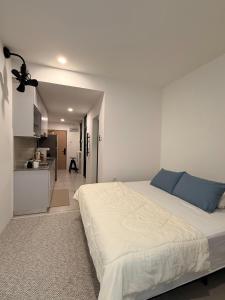 古晋StayCO - D'Millenia Residences - Studio Unit的一间白色卧室,配有一张大床和一个厨房 更多12张照片
