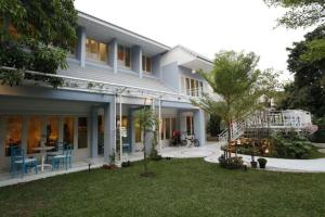 ein weißes Haus mit einem Garten mit einem Baum in der Unterkunft Baan Hmon-Oon in Chiang Mai