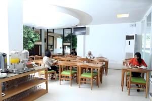 帕朗卡拉亚Fovere Hotel Palangkaraya的一群人坐在餐厅的桌子旁