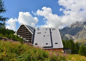 a large building with mountains in the background at Appartamenti La Maison de Vacances in Breuil-Cervinia