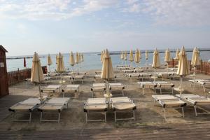 a bunch of chairs and umbrellas on a beach at Hotel Delle Rose in San Bartolomeo al Mare