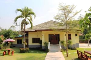 ein gelbes Haus mit einer Palme davor in der Unterkunft OYO 769 Ban Thassanee in Ban Muang Wa