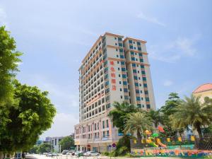 un edificio alto con palme di fronte di Vienna Classic Hotel Qingyuan Taihe Ancient Cave Scenic Area a Xiaoshi