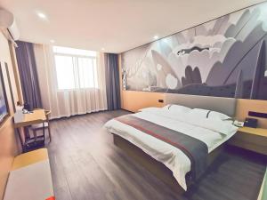 una camera da letto con un letto grande e un dipinto sul muro di Thank Inn Plus Hotel Jiangyin University a Wuxi