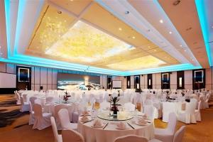 una grande sala banchetti con tavoli e sedie bianchi di New Century Hangzhou Grand Hotel a Xiaoshan Altre 271 foto