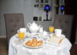 a table with a white table cloth with breakfast foods and orange juice at Chambre d'Hôtes La Villa Molina in Besançon
