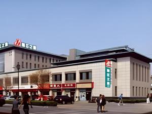 pessoas que atravessam uma rua em frente a um edifício em Jinjiang Inn Yantai Penglaige Zhonglou North Road em Penglai