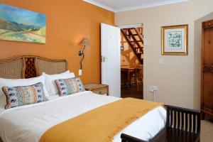 a bedroom with a large white bed with orange walls at Stonecutters Lodge in Lydenburg