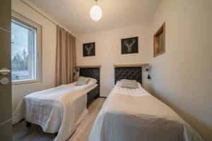 two beds in a room with a window at Lomavuokra Alpine Chalets Tunturinlaita in Levi