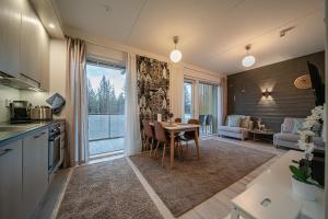 a kitchen and dining room with a table and a living room at Lomavuokra Alpine Chalets Tunturinlaita in Levi