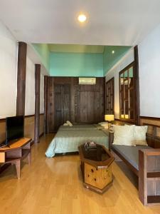 a bedroom with a bed and a couch and a tv at อัมพวาริเวอร์วิว Amphawa River View in Samut Songkhram