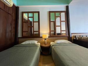 two beds in a room with two windows at อัมพวาริเวอร์วิว Amphawa River View in Samut Songkhram +10 photos