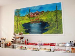 une table avec de la nourriture sur elle avec une peinture sur le mur dans l'établissement Aariana Hotel, à Offenbach-sur-le-Main