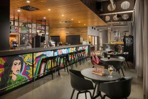a restaurant with a bar with tables and chairs at Moxy London Excel in London