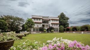 una grande casa bianca con un cortile fiorito di MiraNamin Nest CALACHUCHI - Cozy Room in Historic Home - Indoor Plunge Pool, Petite Desk, Garden View with Balcony, Self-Service Breakfast, Guest Kitchen, Rooftop, Pet-Friendly a Manila