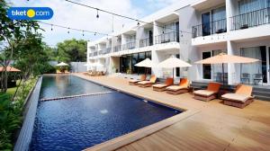una piscina di fronte a un edificio con sedie e ombrelloni di Double G Resort Anyer a Babagan