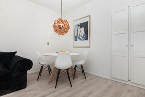 een eetkamer met een witte tafel en een kroonluchter bij Sea View Apartment in Zandvoort