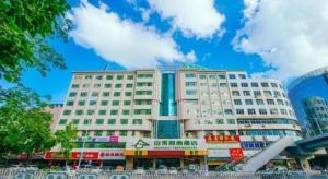 un grande edificio bianco con negozi di fronte di Zhaoqing Shanshui Fashion Hotel Duanzhou Road Branch a Zhaoqing