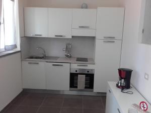 eine Küche mit weißen Schränken und einem Waschbecken in der Unterkunft Ca du Chicco in Cannero Riviera