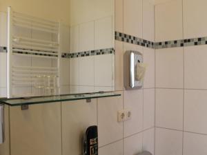 a bathroom with white tiled walls and a glass shelf at Aariana Hotel in Offenbach