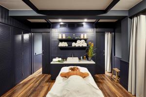 a man laying in a bed in a bathroom with a sink at Delamar 4*Sup-Adults only (18+) in Lloret de Mar