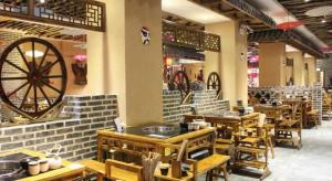 ein Restaurant mit Holztischen und einem großen Rad an der Wand in der Unterkunft 7 Days Inn Weihai High-Speed Railway & Bus Station in Weihai