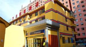 呼和浩特7 Days Inn Hohhot Hailiang Xinhua Square Metro Station的一座黄色的大建筑,旁边有一个标志