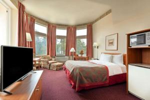 ein Hotelzimmer mit einem Bett und einem Flachbildfernseher in der Unterkunft Ramada by Wyndham SeaTac Airport North in Allentown