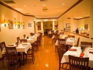 a dining room with white tables and wooden chairs at Garden Plaza Hotel in Passaic Junction