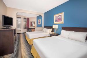 a hotel room with two beds and a flat screen tv at Baymont By Wyndham Laurel in Laurel